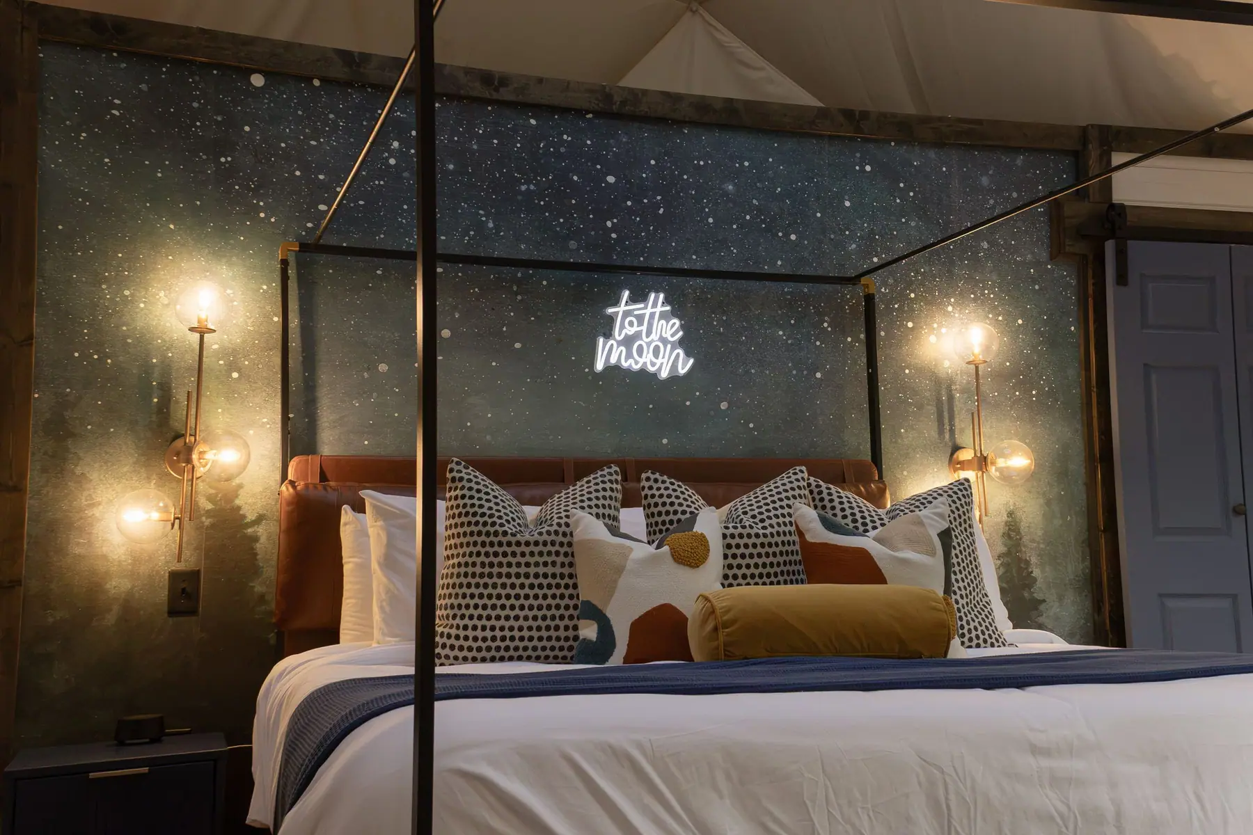 King bed inside the dome under a starry 'to the moon' headboard with glowing sconces