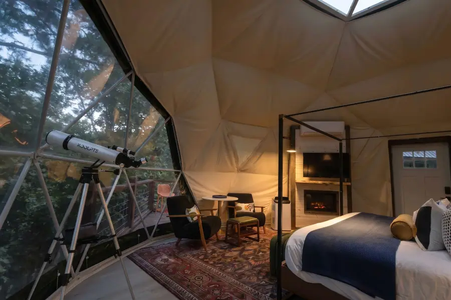 Dome interior with fireplace, armchairs, rug and telescope