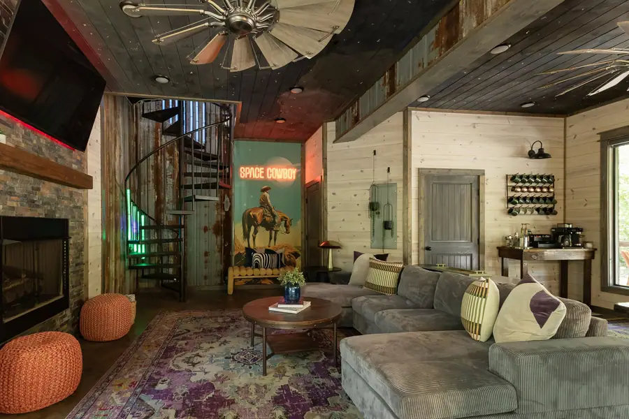 Living room with sectional, fireplace, windmill ceiling fan and spiral stairs