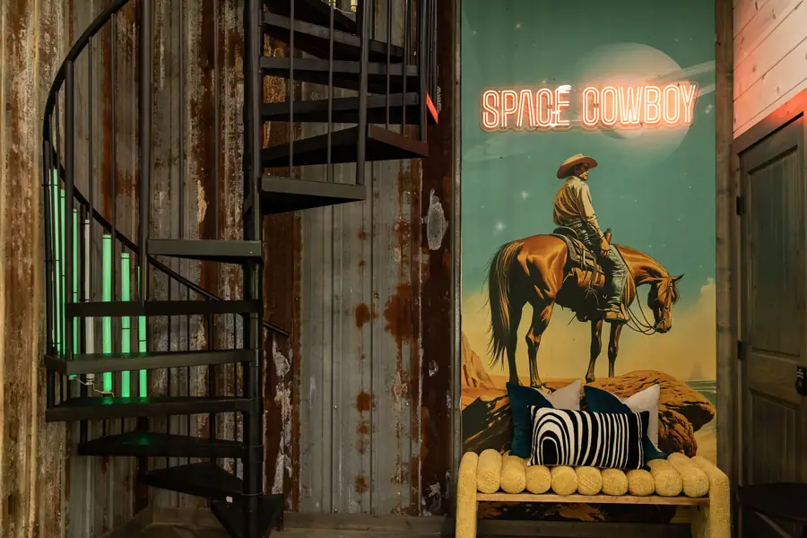 Spiral staircase beside a tall Space Cowboy mural of a cowboy on horseback