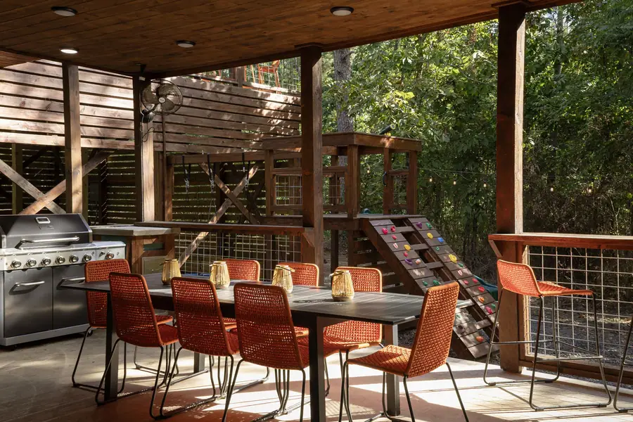 Covered outdoor dining for ten with orange chairs and grill