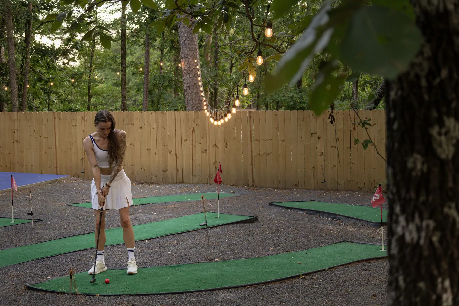 Guest putting on the mini golf course under string lights
